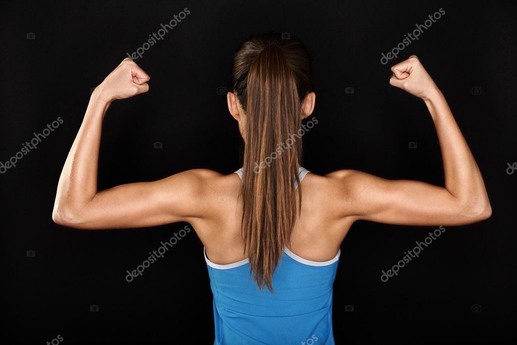 Muscular woman in gym showing back muscles. Strong fitness girl