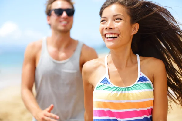 Jeune couple heureux riant en s'amusant sur la plage — Photo