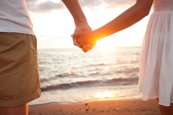 夏日的一对恋人在日落时分手牵手在海滩上 — 图库照片