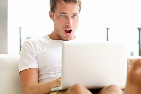 Schockierter Mann schaut auf Laptop — Stockfoto