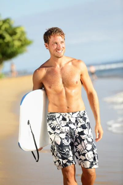 Человек на пляже с кузовом для серфинга — стоковое фото