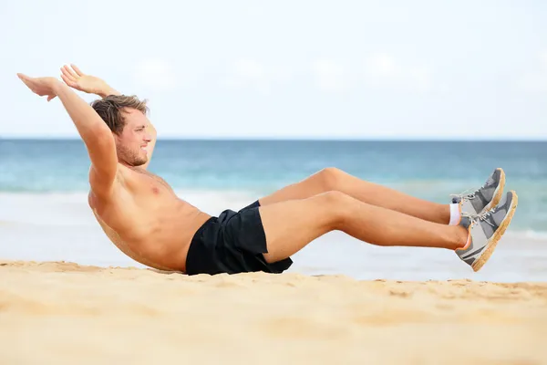 Fitness man gör crunches sit-ups på stranden — Stockfoto