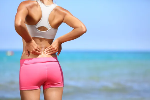 Back pain - Athletic woman rubbing her back Stock Photo