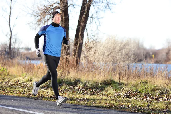 Manliga löpare man kör under hösten på kall dag — Stockfoto