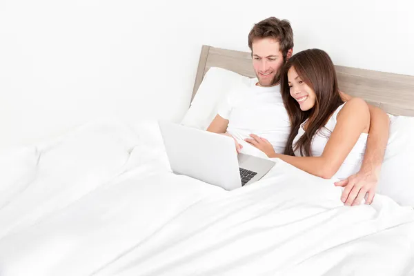 Pareja de cama feliz en el ordenador portátil en el dormitorio — Foto de Stock