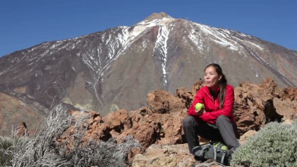 Wandelen. Woman eten apple na wandeling op de teide. — Stockvideo