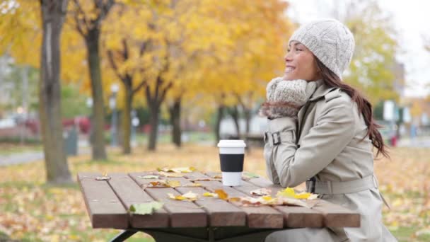 Mujer caída sentada en el parque de otoño sonriendo feliz — Vídeo de stock