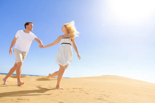 Coppia tenendosi per mano correre divertendosi sotto il sole — Foto Stock