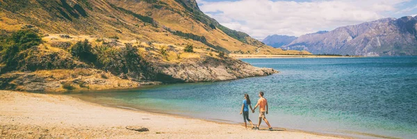 Nueva Zelanda viaje pareja turistas caminando en la orilla del lago Hawea en la región de Otago, Wanaka, paisaje natural. Hombre y mujer tramping excursionistas aventura estilo de vida banner panorama — Foto de Stock