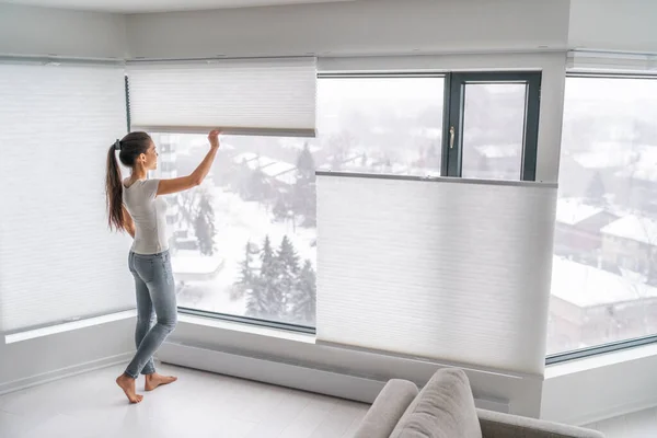 Жінка відкриває домашні штори в міському кондомініумі. Сучасні зверху вниз вниз приватність стільникові відтінки на вікні квартири зберігають тепло взимку з стільниковою завісою. Бездротові плісировані відтінки — стокове фото