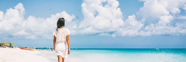 Lujosa mujer viajera de vacaciones en la playa relajándose en el paraíso destino de vacaciones tropicales para una escapada de sol. Chica vistiendo vestido de playa caminando bandera panorámica. —  Fotos de Stock
