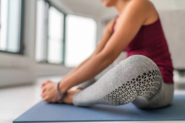 Yoga studio klasse vrouw stretching benen op trainingsmat. Zittend vlinderbeen met voetzolen samen met handen. Sluiting op de benen — Stockfoto