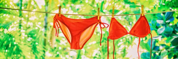 Roter Bikini-Badeanzug, der an der Wäscheleine hängt und draußen im Garten trocknet. Grüner Hintergrund Panorama Banner Header — Stockfoto