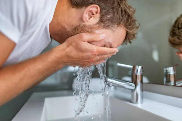 Hombre lavado de cara en el baño lavado de limpieza para el tratamiento facial del acné en el fregadero salpicando agua fría en la cara. Hombres belleza cuidado de la piel estilo de vida —  Fotos de Stock