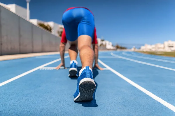 Sprinter en la línea de salida esperando para comenzar la competición de carreras en pista y campo fuera del estadio. Atleta corredor hombre corriendo al aire libre — Foto de Stock