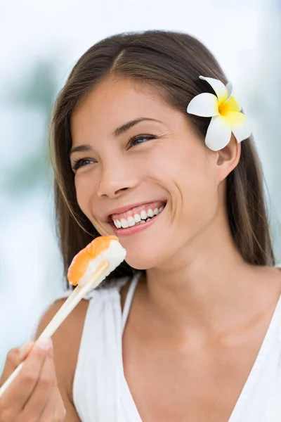 Счастливая азиатка, питающаяся японской едой, суши из лосося нигири на открытой террасе ресторана летом. Смешанная раса азиатская кавказская девушка улыбается со здоровой диетой из свежих продуктов. — стоковое фото