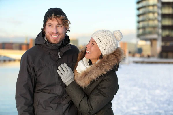 Casal de inverno com chapéu de neve e casacos. Jovens adultos felizes caminhando juntos sorrindo em uma rua da cidade desfrutando de uma caminhada urbana ensolarada no bairro moderno. Asiático namorada no amor com o homem. — Fotografia de Stock