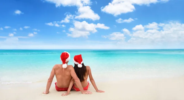 Boże Narodzenie plaża wakacje święto kapelusz para relaks od tyłu siedzi na białym piasku szerokie horyzontalne tło nieba dla reklamy tekstowej na sezon wakacyjny. Tekstura niebieskiego oceanu. — Zdjęcie stockowe