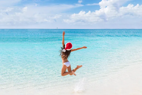 Felice Santa ragazza cappello salto di gioia e divertimento in vacanza di Natale viaggio in destinazione spiaggia tropicale. Vacanza invernale donna fuga. — Foto Stock