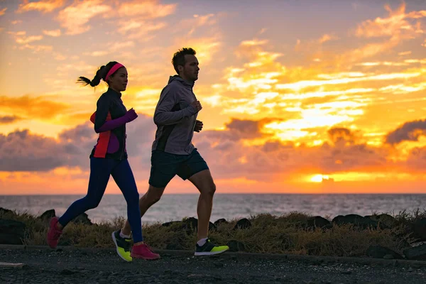 Mensen trainen cardio samen actieve vrienden joggen in de vroege ochtend zonsopgang op het strand. Run fit paar hardlopers vrouw en man loopt buiten. Silhouetten van twee atleten die trainen — Stockfoto