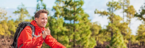 Eten granola bar snack op bos wandeling happy camper man wandelen in de natuur landschap met gezonde voeding ontbijt bar. Banner panoramisch — Stockfoto