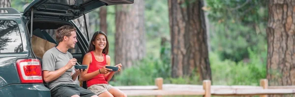 Road trip couple tourist eating food lunch at back of car on summer camping vacation travel. Happy driving people — Stock Photo, Image