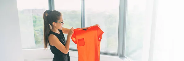 Online winkelen panoramische gewas. Een nieuw kledingconcept kopen. aziatische vrouw blij kijken naar oranje zijde top van kleding winkel banner — Stockfoto