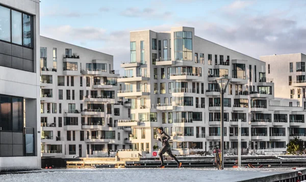 コペンハーゲン市は冬のランニングマンが街中でカーディオを訓練するコペンハーゲンのアパートビルをジョギングしている。寒い気候の中でアクティブな健康的なライフスタイルの男のランナー屋外 — ストック写真