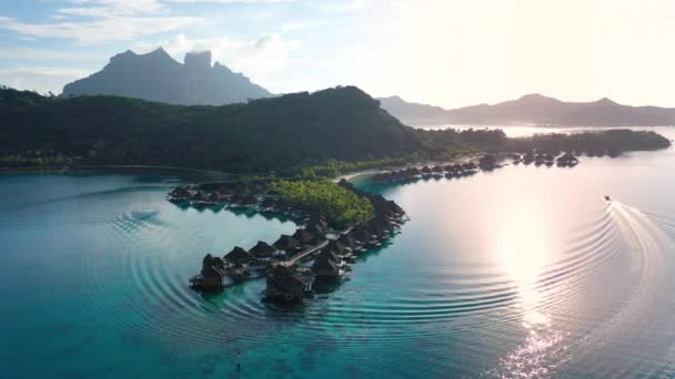 Podróże wakacje lotnicze drone wideo luksusowe bungalowy nad wodą resort w lagunie rafy koralowej ocean przez plażę. Zachód słońca w raju ucieczka Bora Bora, Polinezja Francuska, Tahiti, Południowy Ocean Spokojny — Wideo stockowe