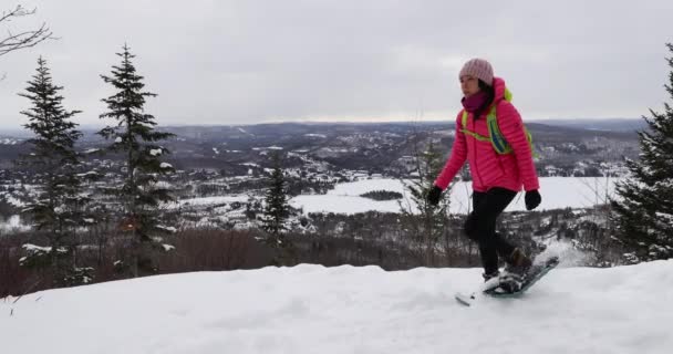 Mujer raquetas de nieve en el bosque de invierno senderismo en el idílico paisaje de invierno. Personas en caminata en la nieve en raquetas de nieve que viven estilo de vida activo al aire libre. Mont Tremblant, Laurentians, Quebec, Canadá — Vídeos de Stock
