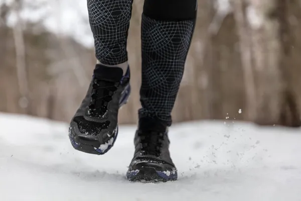 Zimowe buty do biegania kobieta trening cardio na świeżym powietrzu jogging na białym śniegu w zimną pogodę. Zbliżenie stóp w obuwiu fitness — Zdjęcie stockowe