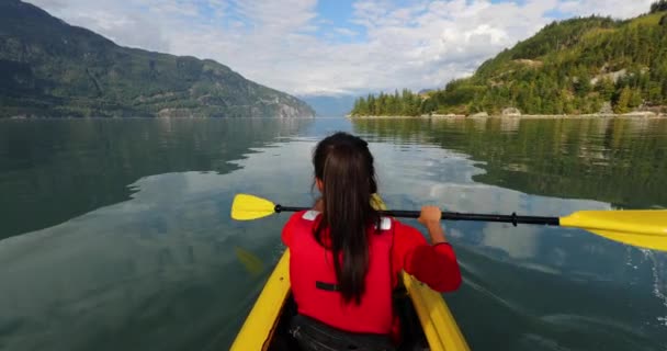 女子皮划艇在斯卡拉米什划桨在皮划艇在豪湾一个峡湾周围是山。加拿大不列颠哥伦比亚省生活在积极的室外健康生活方式中的人 — 图库视频影像