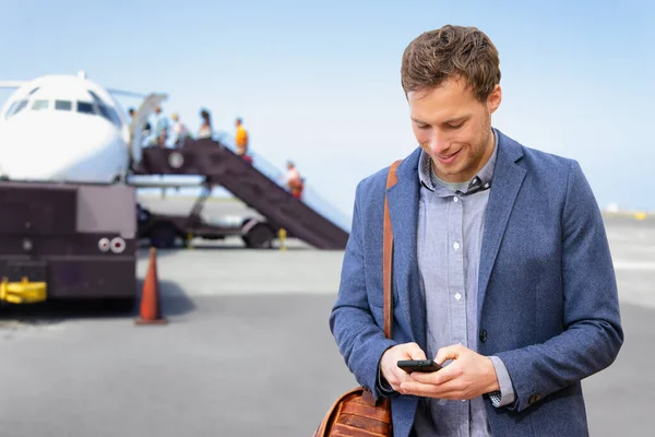 Αερολιμένας άνθρωπος γραπτών μηνυμάτων στο τηλέφωνο αφήνοντας για επαγγελματικό ταξίδι. Επιχειρηματίας σε αεροπλάνο επιβίβασης smartphone. Νεαρός επαγγελματίας άντρας που χρησιμοποιεί δεδομένα 5g σε εφαρμογή smartphone κατά την πτήση φορώντας κοστούμι και τσάντα laptop. — Φωτογραφία Αρχείου