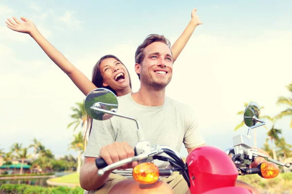 Šťastný mladý pár těší skútr jízda proti obloze. Veselá žena se zdviženou paží při řízení vozidla. Bezstarostní turisté si užívají letní dovolenou. — Stock fotografie