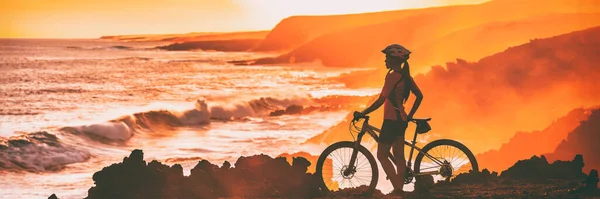 Rowerzysta sportowy patrząc na ocean plaży linii brzegowej podczas trasy rowerowej wyścigu. Sylwetka kobiety trening atleta rower górski na zewnątrz o zachodzie słońca, panorama baner. — Zdjęcie stockowe