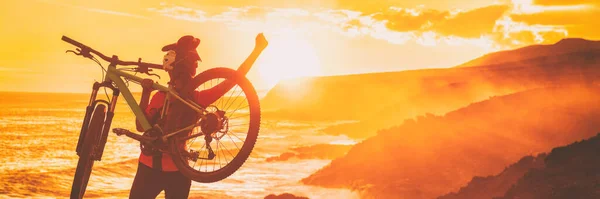 Mountain bike ciclista vincente gara con le braccia alzate nel successo, realizzazione, realizzazione e vincita. Happy MTB donna in bicicletta alzando le braccia durante il tramonto tifo alla costa sentiero. — Foto Stock