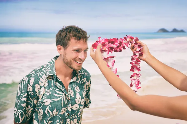 Collar de guirnalda de flores de lei hawaiano gesto de bienvenida de dar la bienvenida a las orquídeas turísticas en la playa de Hawaii. Hombre feliz recibiendo regalo tradicional en vacaciones tropicales de verano. —  Fotos de Stock