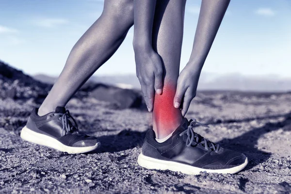 Lesión deportiva - mujer corredora en el sendero corriendo sosteniendo doloroso tobillo con dolor. Círculo rojo para mostrar área inflamada del accidente en la pierna. —  Fotos de Stock