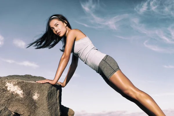 Entrenamiento de fuerza fitness mujer ejercitando el núcleo con el ejercicio de empuje en ángulo hacia arriba en el rock. Atleta asiático haciendo ejercicio con ejercicios de peso corporal para tonificar el cuerpo. Entrenamiento en verano desierto paisaje. —  Fotos de Stock