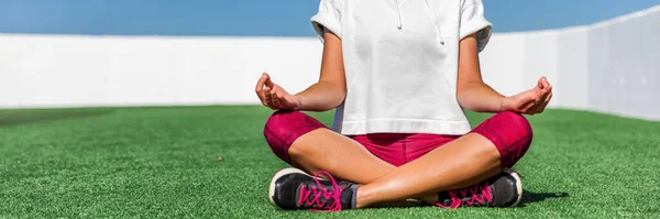 Yoga-Fitness-Sportlerin meditiert in Lotus-Pose im Gras sitzend. Panorama-Bannerschnitt von Leggings und Schuhen in Aktivbekleidung. Beine und Füße des Unterkörpers. — Stockfoto