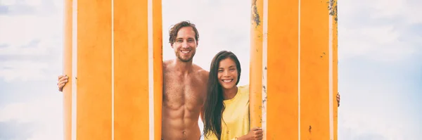 Surfistas pareja feliz sosteniendo tablas de surf naranja. Surf playa estilo de vida joven pareja en vacaciones de verano banner panorama. —  Fotos de Stock
