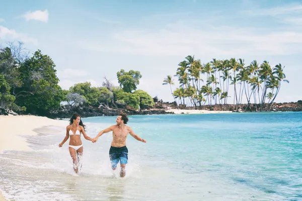Playa divertida vacaciones de verano pareja corriendo juntos feliz. Hawaii vacaciones isla de playa de viaje. Mujer asiática en bikini, hombre joven. — Foto de Stock