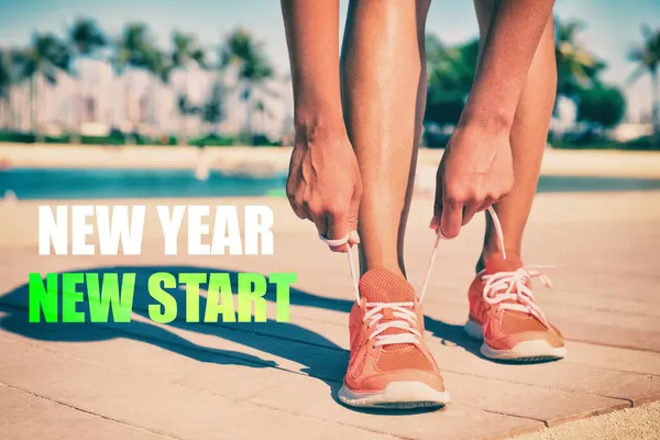 New Year New Start fitness new year resolution runner woman tying up laces of running shoes getting ready to run for weight loss. Athlete on summer beach