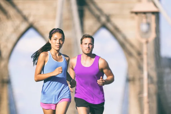 Corredores da cidade de Nova York treinando para maratona na ponte Brooklyn NYC em paisagem urbana. Fit jovem casal fazendo sua rotina de exercícios em um dia de verão . — Fotografia de Stock