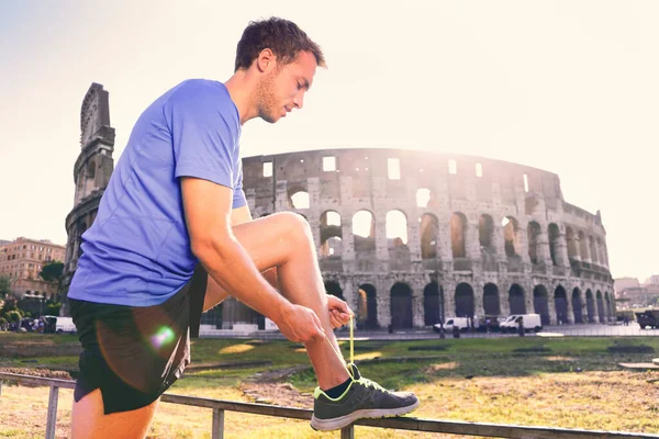 Running shoes man runner athlete tying shoe laces. male sport fitness active lifestyle person getting ready for jogging outdoors on Rome city street in summer at Colosseum in Rome, Italy. — Stock Photo, Image