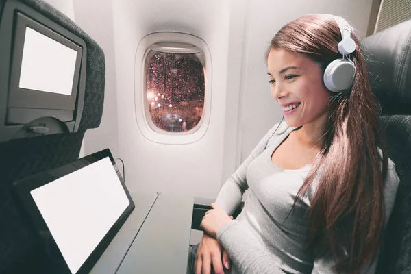 Pasajero en avión usando tableta. Mujer en cabina de avión usando un dispositivo inteligente escuchando música en auriculares. Pancarta panorámica viajes gente estilo de vida. —  Fotos de Stock