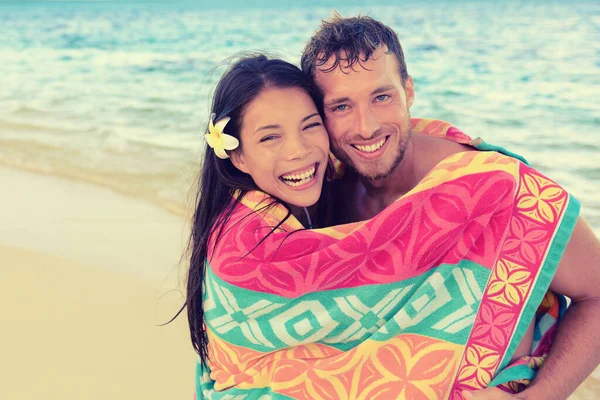 Söt sommar semester unga interracial par har kul lekfull under stranden handduk tillsammans skrattar. Glada vänner kramas, asiatisk kvinna, vit man. — Stockfoto