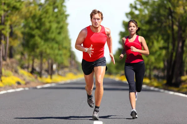 Running γυμναστήριο ζευγάρι των δρομέων κάνει αθλητισμό στο δρόμο εξωτερική. Ενεργός άνθρωπος διαβίωσης και γυναίκα τζόκινγκ εκπαίδευση καρδιο σε εξωτερικούς χώρους καλοκαίρι φύση. Ασιάτισσα, καυκάσια αθλήτρια. — Φωτογραφία Αρχείου