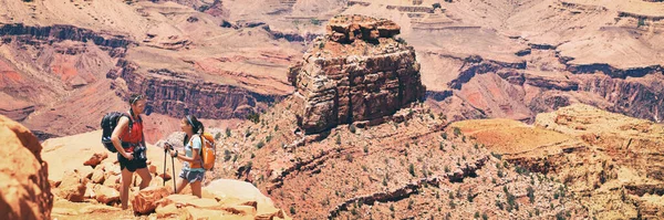 Caminhantes casais turísticos caminhadas em trilha de caminhada no Grand Canyon National Park com caminhadas pólos e mochilas, bandeira da paisagem com espaço de cópia no fundo. — Fotografia de Stock