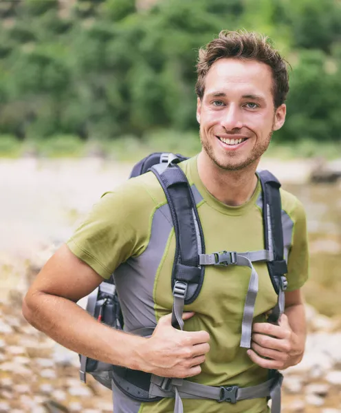 活泼的年轻人在户外徒步旅行时的肖像.年轻的男性徒步旅行者带着背包开心地笑着，因为他们在森林中远足时，带着背包去野外露营。白人男性模式. — 图库照片